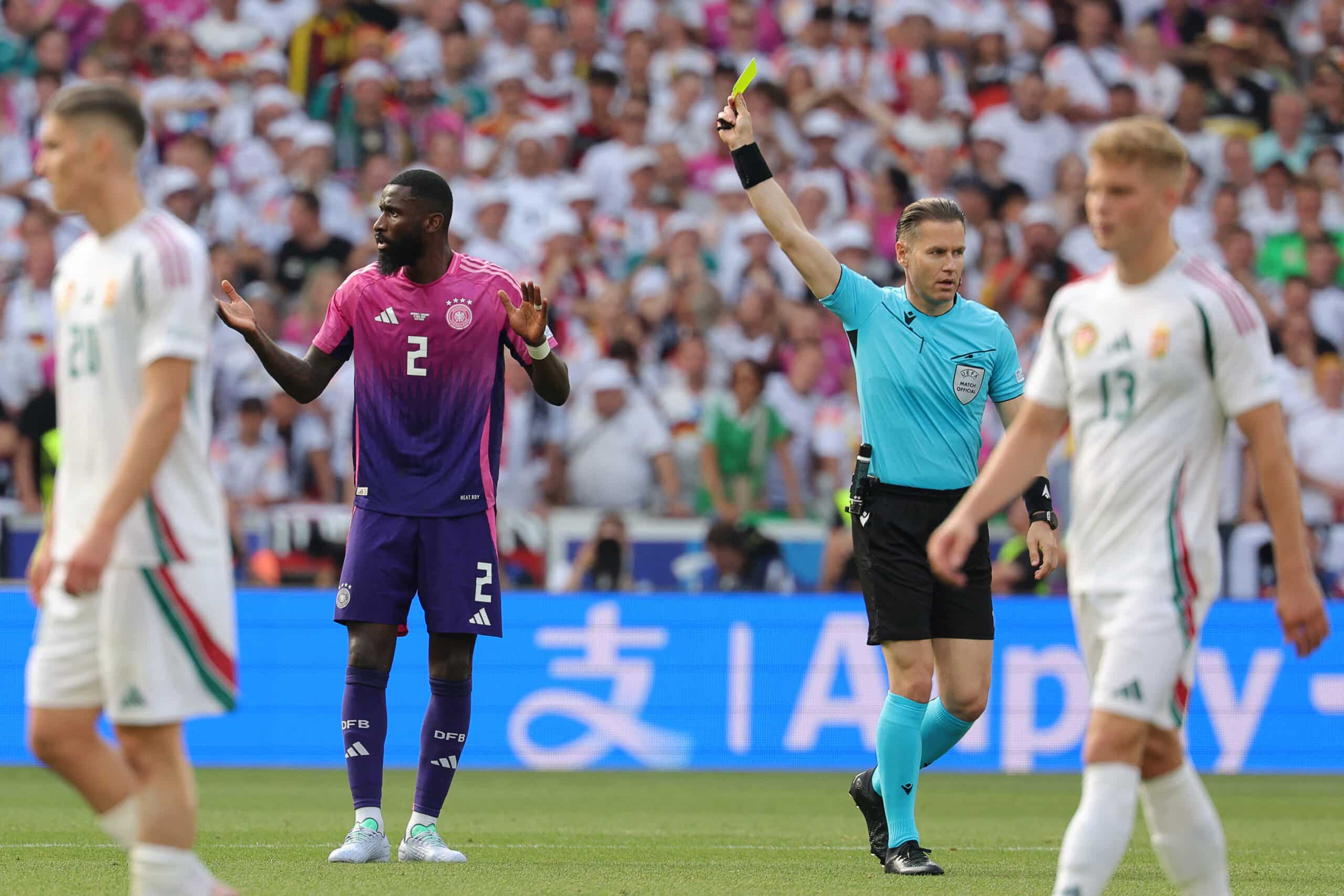Gelbe Karten Regelung bei der EM 2024 - Wann wird ein Spieler gesperrt? Der deutsche Verteidiger Antonio Rüdiger (Nr. 02) erhält vom niederländischen Schiedsrichter Danny Makkelie während des Fußballspiels der UEFA Euro 2024 Gruppe A zwischen Deutschland und Ungarn in der Stuttgarter Arena am 19. Juni 2024 eine gelbe Karte. (Foto: LLUIS GENE / AFP)
